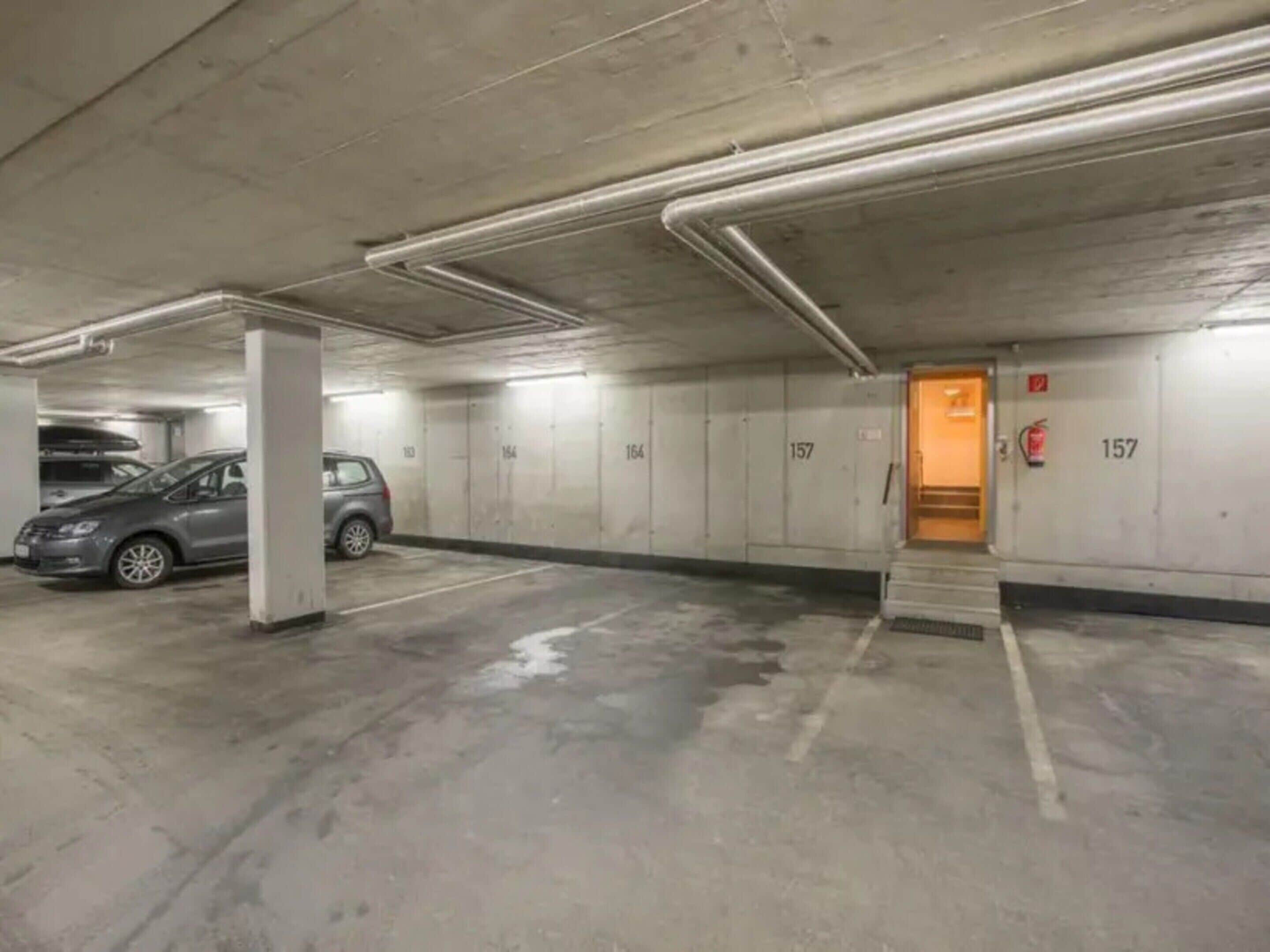 A parking garage with concrete walls, numbered parking spaces, and a fire extinguisher.