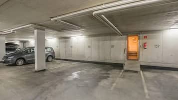 A parking garage with concrete walls, numbered parking spaces, and a fire extinguisher.