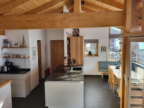 A modern kitchen with a central island, wooden cabinets, and a dining area with a table and chairs.