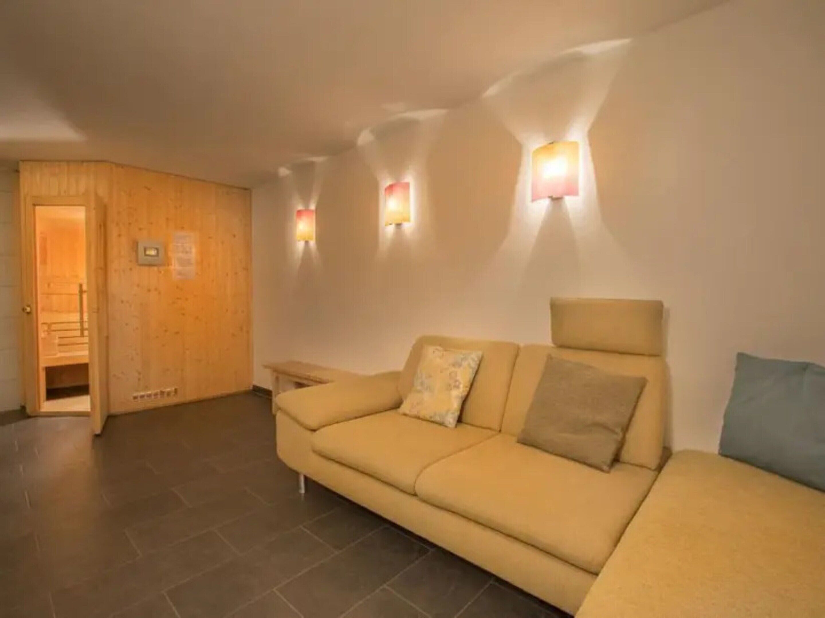 A room with a beige sofa, a wooden wall, and a small table.