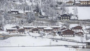 A snow-covered village with traditional chalet-style buildings, a ski lift, and a mountain backdrop. - Austrian Mountain Chalet Retreat (Wald im Pinzgau)