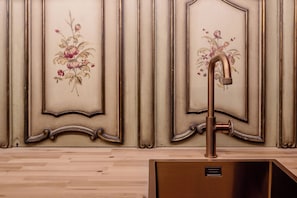 Un baño de estilo vintage, con un panel decorativo en la pared con motivos florales y un grifo clásico.