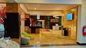 A hotel lobby with a reception desk, seating area, and a television screen. - Tribu Hotel (Enugu)