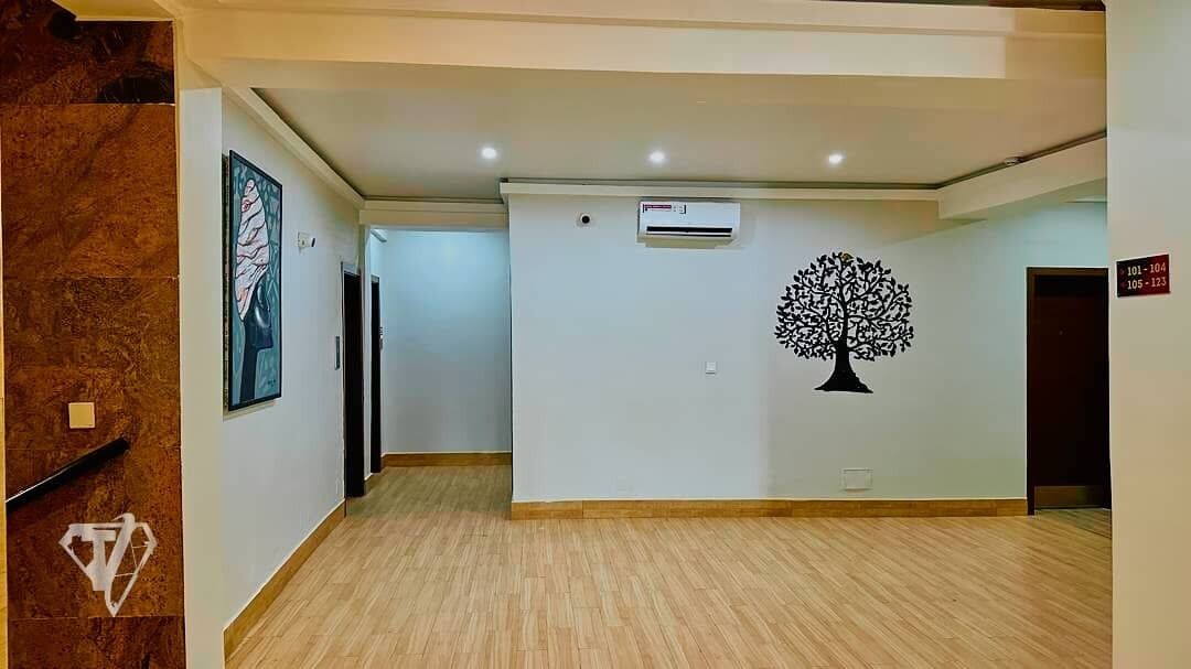 A hallway with a marble wall, a framed artwork, an air conditioning unit, and a wall-mounted tree decoration.