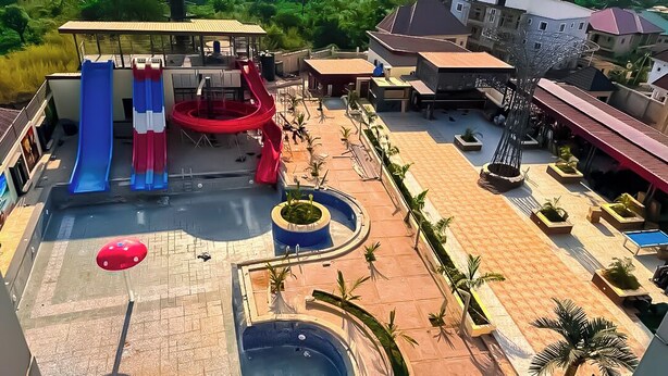 A pool area with multiple slides, a hot tub, and outdoor seating. - Tribu Hotel (Enugu)