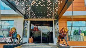 A building entrance with two lion statues, a modern design, and a glass door. - Tribu Hotel (Enugu)