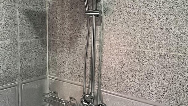 A shower with a handheld showerhead and a wall-mounted faucet. - Tribu Hotel (Enugu)