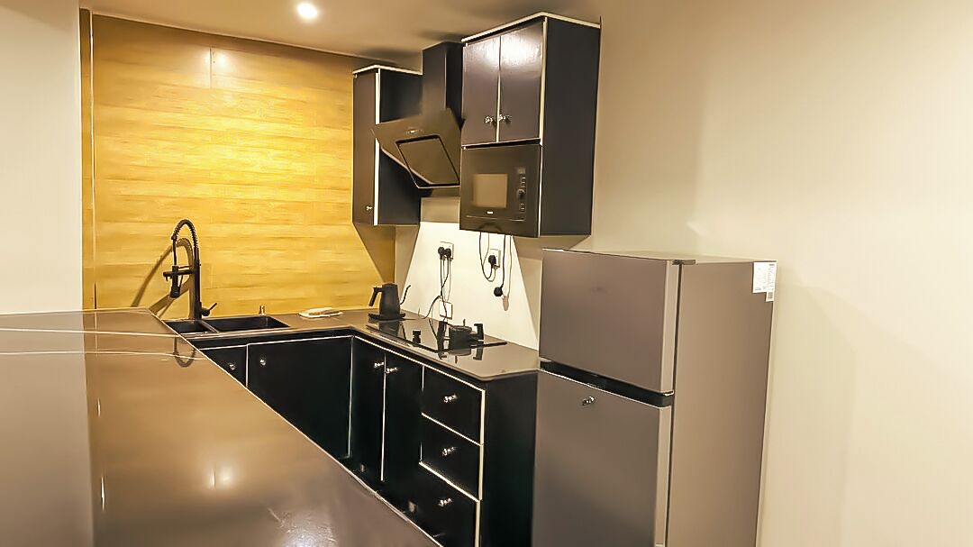 A modern kitchen with stainless steel appliances, black cabinetry, and a wooden accent wall.