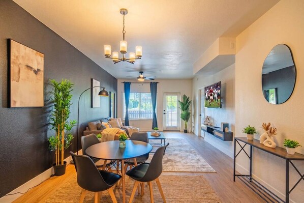A modern living room with a dining area, featuring a sofa set, a coffee table, and a chandelier.