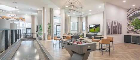 Un espacio interior moderno con mesa de futbolín, zona de estar y televisor.