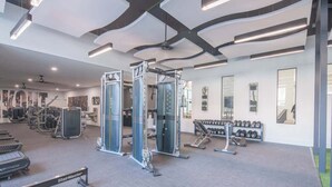 Ein modernes Fitnessstudio mit verschiedenen Trainingsgeräten, darunter Laufbänder, Kraftgeräte und Kurzhanteln.