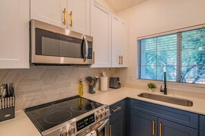 A modern kitchen with stainless steel appliances, white cabinetry, and a window with a view.