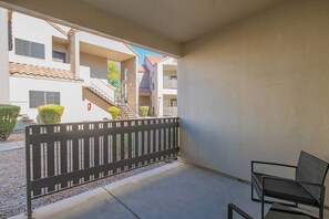 A balcony with a metal railing, a chair, and a building in the background.