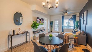 A modern living room with a round dining table, black chairs, a sofa, and a ceiling fan. - Near TPC - Pool, Gym, Hot Tub Pickleball, WD (Scottsdale)