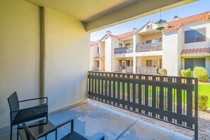 Ein Balkon mit schwarzem Metallgeländer, einem kleinen Tisch und zwei Stühlen.
