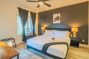 Une chambre d’hôtel avec un lit, des tables de chevet, un bureau et un ventilateur de plafond.