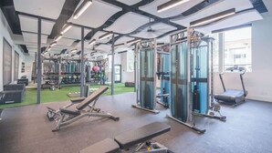 Et fitnesscenter med styrkeløftudstyr, løbebånd og træningsmåtter.