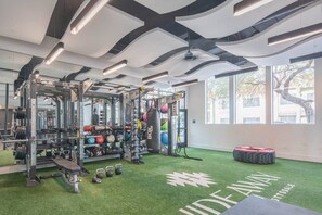Une salle de sport équipée de matériel de musculation, d’un sac de frappe et d’un sol recouvert d’une moquette synthétique verte.