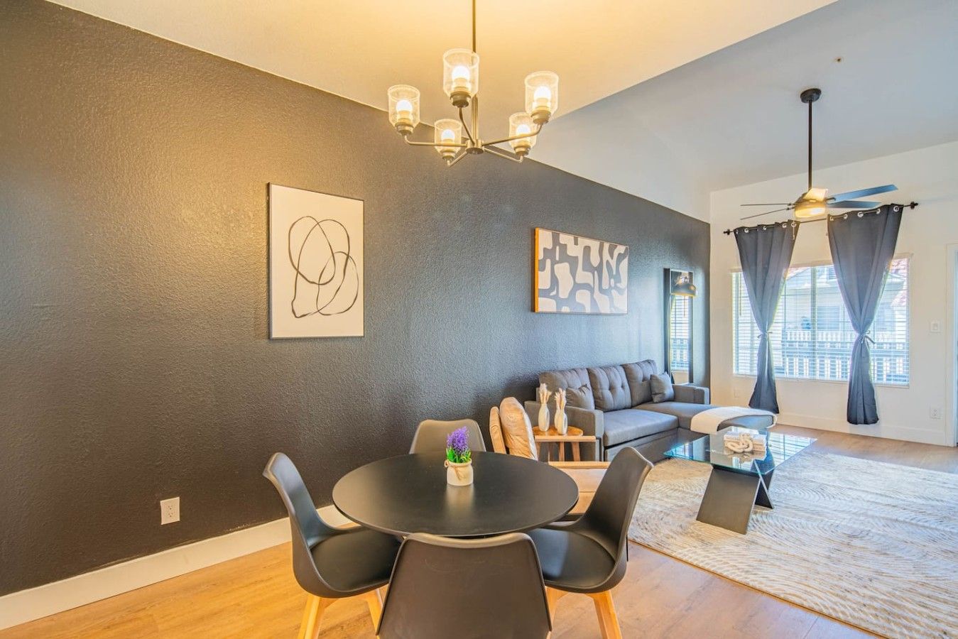 Een moderne woonkamer met een bank, een eettafel, stoelen en kunstwerken aan de wanden.