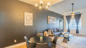 Een moderne woonkamer met een bank, een eettafel, stoelen en kunstwerken aan de wanden.