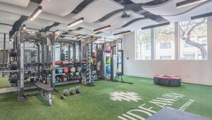 Et fitnessrum med styrkeløbsudstyr, en boksebold og en grøn kunstgræsbane.
