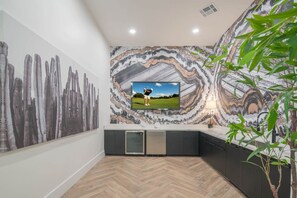 Eine moderne Küche mit großem Fernseher, einem Fischgrätparkett und einer Marmor-Spritzschutzwand.