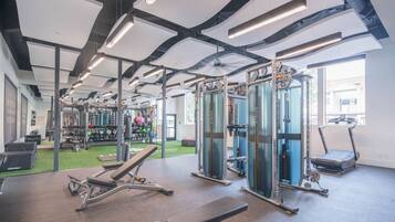 A gym with weightlifting equipment, treadmills, and a green exercise area.