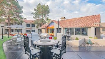 An outdoor patio with a round table and chairs, a grill, and a fountain.
