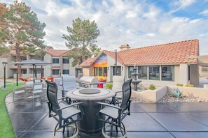 Eine Terrasse im Freien mit einem runden Tisch und Stühlen, einem Grill und einer Fontäne.