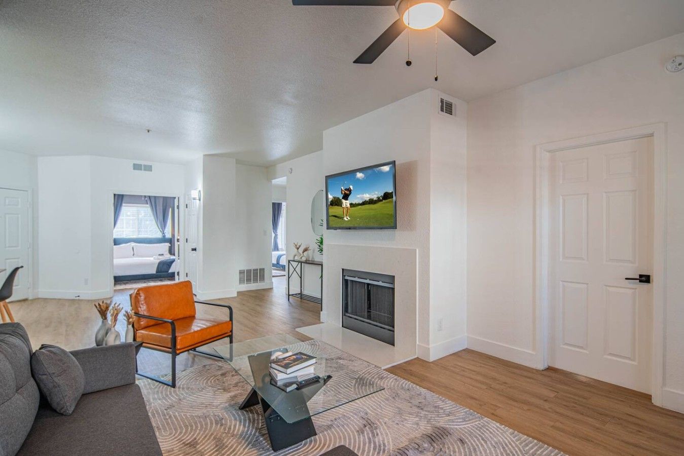 A modern living room with a sofa, a coffee table, a fireplace, and a television mounted on the wall.