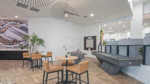 Un espace de détente moderne avec un baby-foot, des sièges confortables et un grand tableau abstrait accroché au mur.