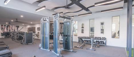 Une salle de sport moderne équipée de divers appareils d’exercice, notamment des machines de musculation et des haltères.