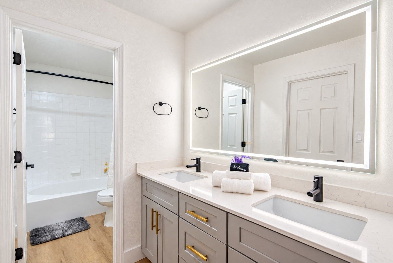 A modern bathroom with a large mirror, two sinks, and a shower area.