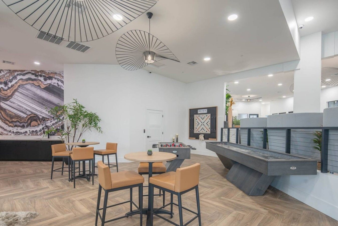 Un intérieur moderne avec un espace salon central, une grande peinture abstraite et un luminaire au plafond original.
