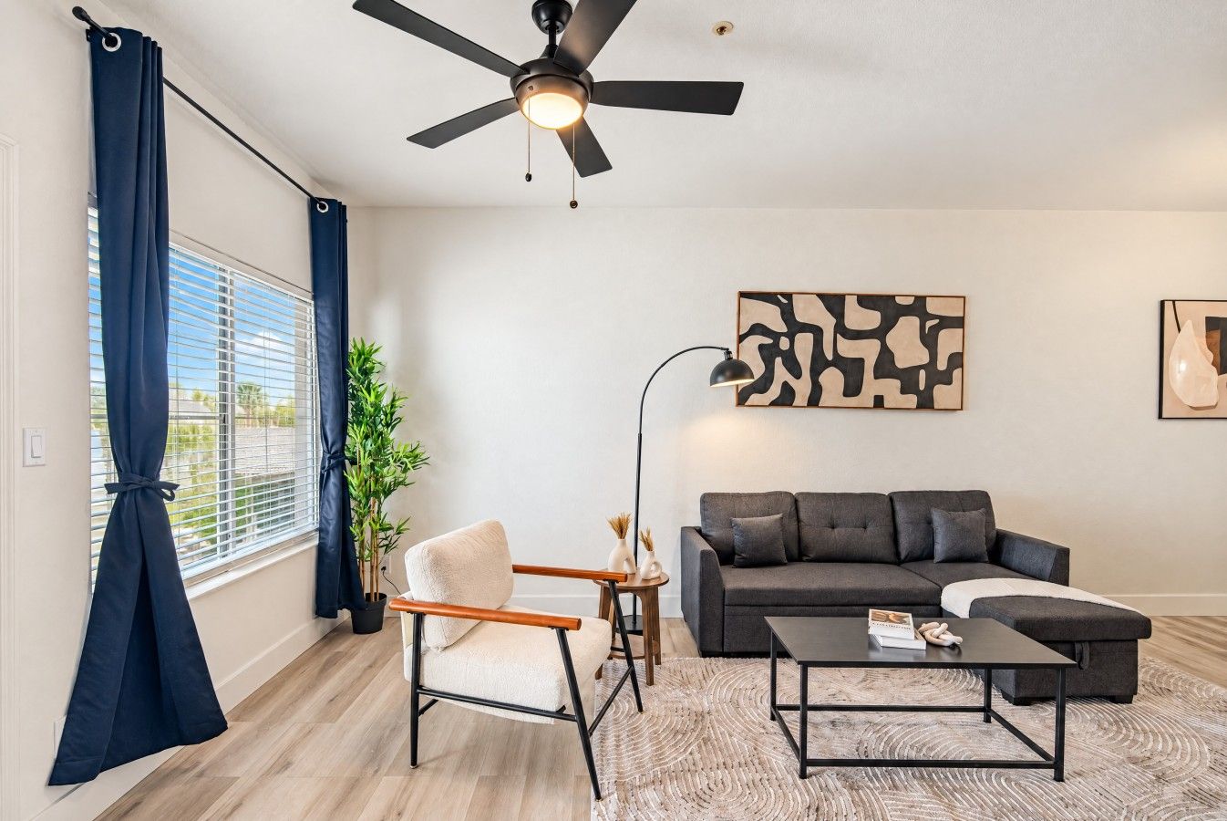 Un salon moderne avec un ventilateur de plafond, un canapé, une table basse et un fauteuil.
