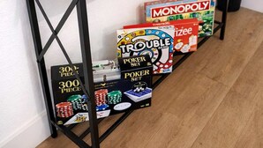 Une console en bois sur laquelle sont posés des jeux de société, comme Jenga, UNO, Monopoly et d’autres.