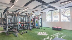 Un gimnàs amb una zona de musculació, equip d'aeròbic i un sòl de gespa artificial.