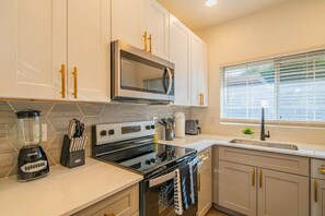 A modern kitchen with white cabinets, a microwave, an oven, and a sink.