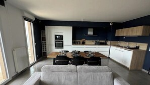 A modern living room with a grey sofa, a dining table set for four, and a kitchen in the background. - Luxurious 5 pc + Jacuzzi + rooftop + terrace + air conditioning (Montpellier)