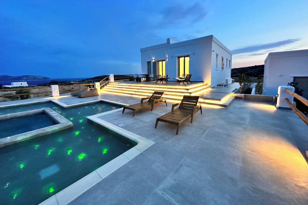 A modern outdoor pool area with lounge chairs and a small pool, surrounded by a white building with steps leading up to a terrace.