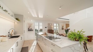 A modern kitchen with white cabinetry, a large island, and a view to the dining area.