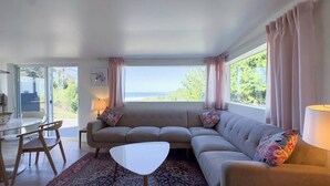 Un salon avec un canapé, une petite table et une vue sur la mer.