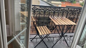 A balcony with a wooden table and chairs, surrounded by a decorative metal fence. - Apartment in Gentilly, 2 steps from Paris (Gentilly)