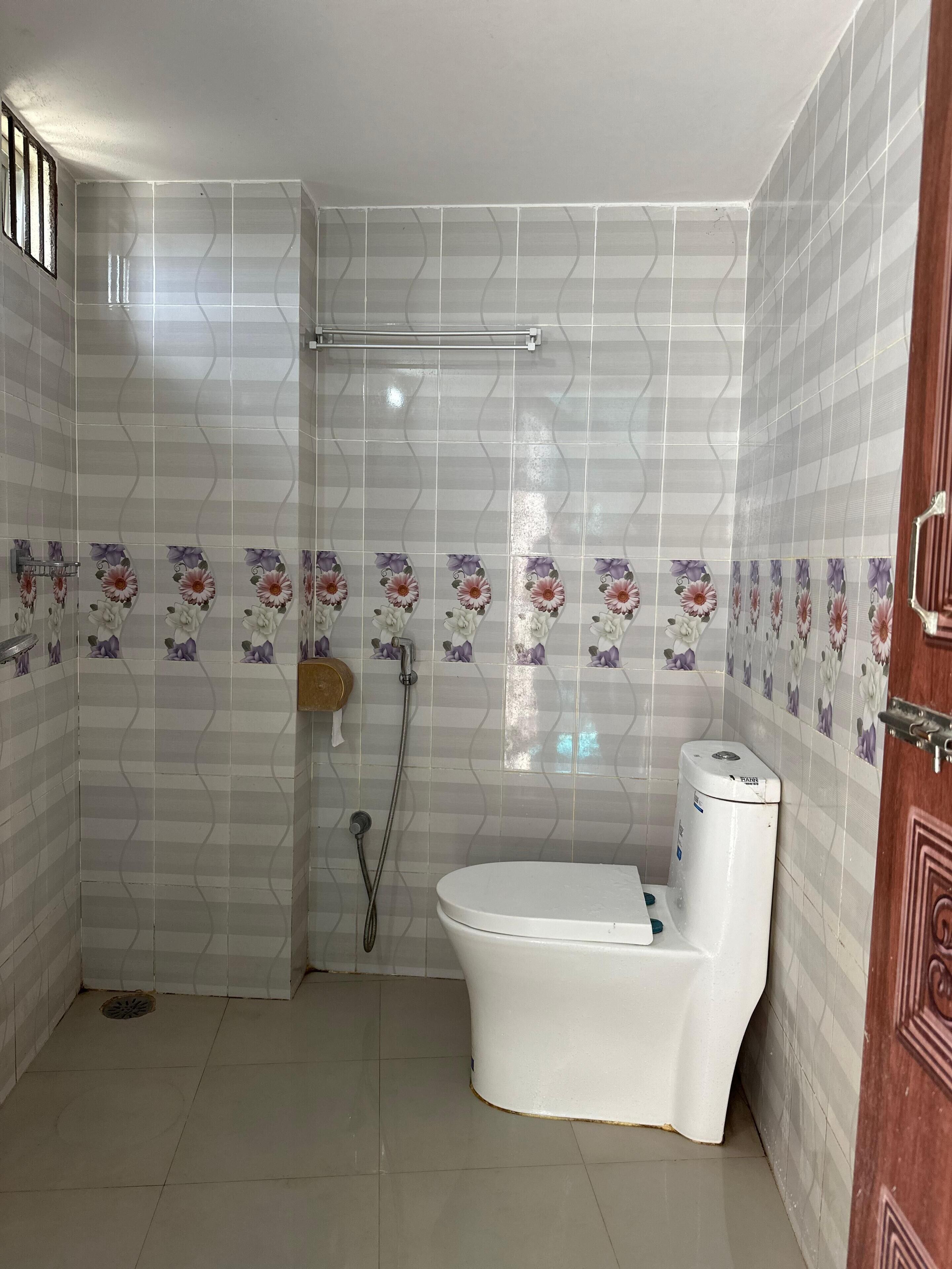 A bathroom with a toilet, shower, and tiled walls.