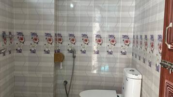 A bathroom with a toilet, shower, and tiled walls.