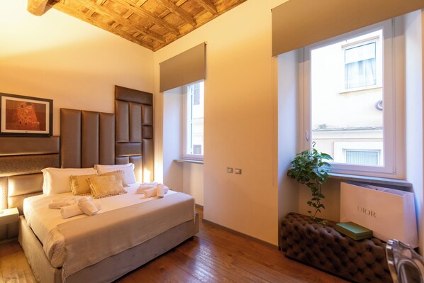 A bedroom with a bed, bedside tables, a headboard, a window, a radiator, and a plant. - Fontana di Trevi Roma Luxury Suite (Rome)