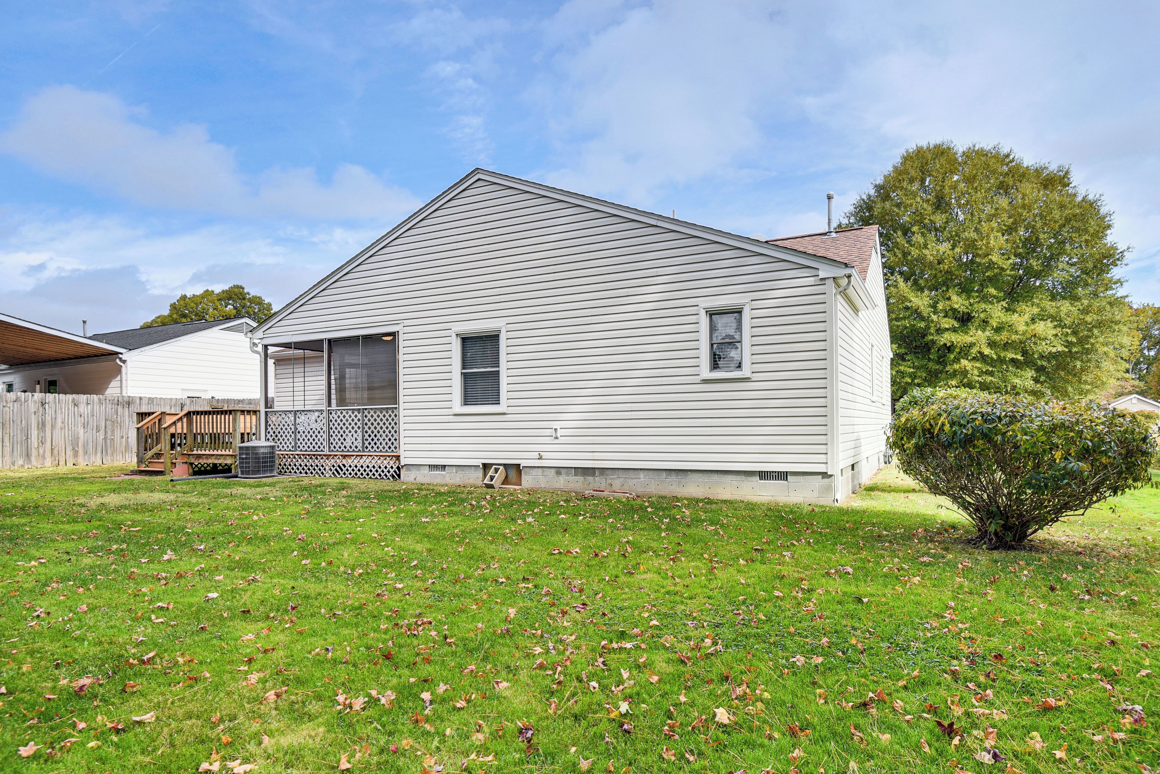 A single-story house with a front porch, a small front yard, and a wooden deck.