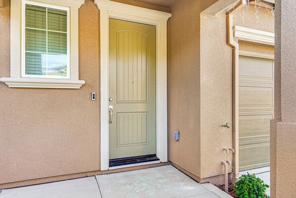 A beige house with a white front door, a window with blinds, and a garage door.