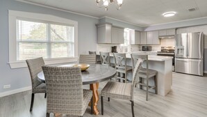A modern kitchen with grey cabinetry, a central island, and a dining area with wicker chairs. - Hike, Fish & Boat: Secluded Mountain View Home (Mountain View)