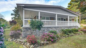 A house with a covered porch, stone foundation, and a garden with various plants and flowers. - 4 Mi to Falls Lake: Dog-friendly Wake Forest Home (Wake Forest)